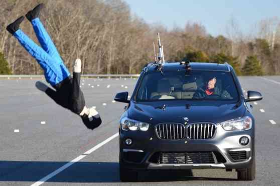 A BMW coming towards the viewer having hit a manniquin into the air